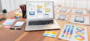 a laptop and several pieces of paper showing an Appnet designer's web design process for mobile devices